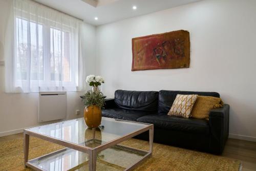 - un salon avec un canapé noir et une table en verre dans l'établissement 2 bedroom apartment w/ courtyard at Croisé Laroche, à Marcq-en-Barœul