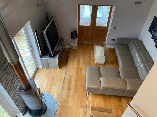 ein Wohnzimmer mit einem Sofa und einem TV in der Unterkunft Winnie Cottage - Hot Tub, Games Room, Sauna, Large Garden in Stocksfield