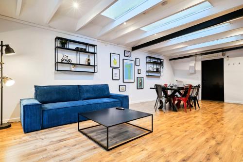 Una sala de estar con un sofá azul y una mesa. en Renovated two-bedroom loft veranda, en Tourcoing