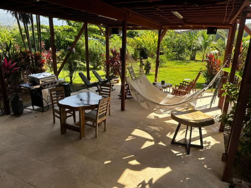 a patio with tables and chairs and a hammock at Uvita Oasis Retreat with Villa Cabins and Apartment in Uvita