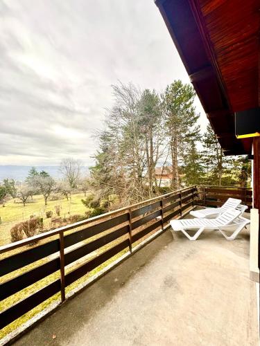 a porch with a white chair and a fence at Appartement spacieux et lumineux - 10 personnes - entre lacs et montagnes in Fillinges