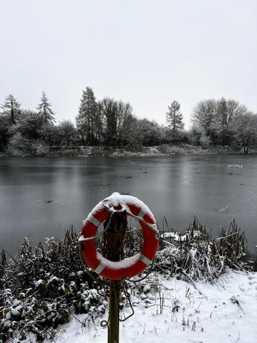 a snow covered stop sign in front of a river at 'Little Grebe' - Secluded Rustic Lodge - Fishermans delight. in York
