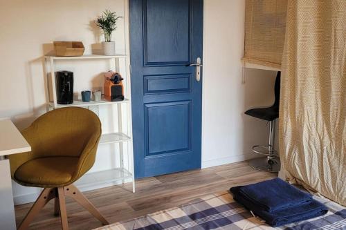 una porta blu e una sedia in una stanza di Chambre indépendante chez l'habitant à la campagne proche bordeaux et l'ange bleu a Gauriaguet