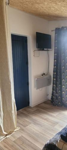 une chambre avec une porte bleue et une télévision dans l'établissement Chambre indépendante chez l'habitant à la campagne proche bordeaux et l'ange bleu, à Gauriaguet