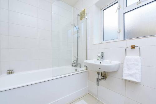 a white bathroom with a sink and a bath tub at Mayfair - Split Level 2 Bed Apartment in London