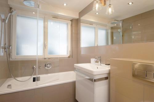 a white bathroom with a sink and a shower at Skirama 015 in Verbier