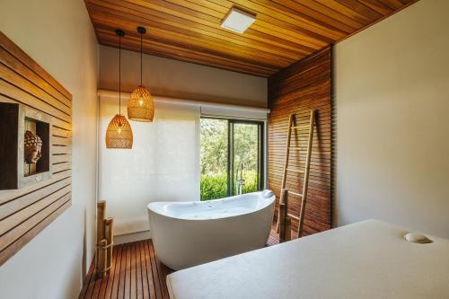 uma casa de banho com uma banheira branca e uma janela em LAS HOTEL BOUTIQUE em Foz do Iguaçu
