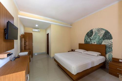 a bedroom with a bed and a flat screen tv at Cove Raddeyapa in Canggu