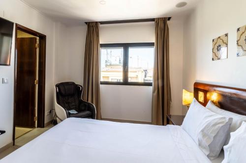 a bedroom with a bed and a chair and a window at Hotel A.S. Lisboa in Lisbon