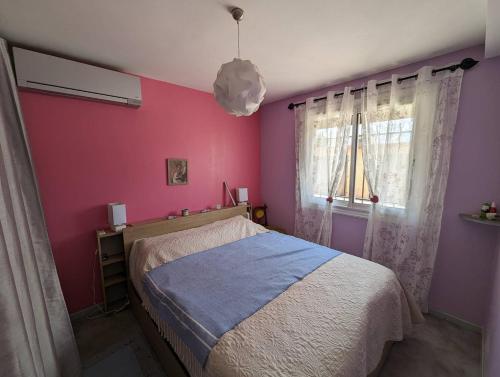 een slaapkamer met een bed en een roze muur bij Appartement en rez de jardin, 2 chambres, plage et commerces à 5 minutes à pied in Six-Fours-les-Plages