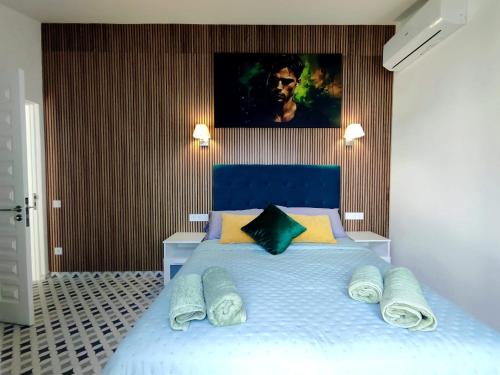 Un dormitorio con una cama azul con una pintura en la pared en Bungalow BAHIA VERDE, en Playa del Inglés