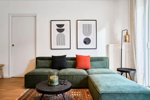 un soggiorno con divano verde e cuscini arancioni di Apartment in a new residence with parking a Mouvaux
