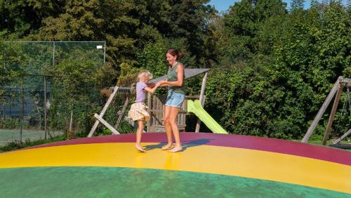 uma mulher e uma criança em pé num trampolim em Camping de Krabbeplaat em Brielle