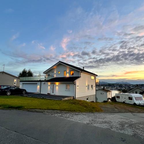 una casa blanca con una puesta de sol en el fondo en 1 roms leilighet sentralt, en Tromsø