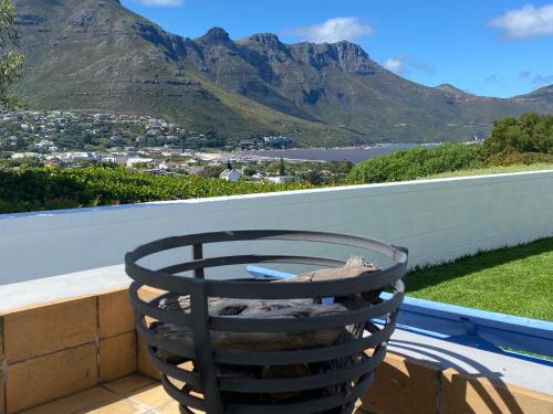 a chair on a balcony with mountains in the background at Cockleshells Beach Cottage in Cape Town