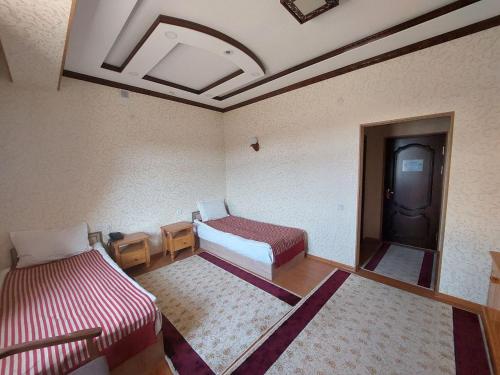 um pequeno quarto com duas camas e uma porta em Hotel Shams Khiva em Khiva
