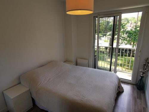 een slaapkamer met een wit bed en een groot raam bij Résidence ORION- Appartement pour 2 à 3 personnes- Wifi gratuit in Seignosse