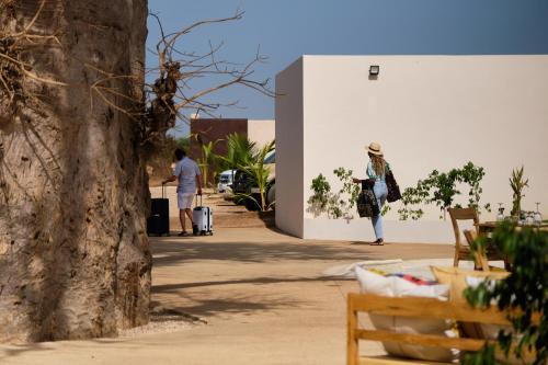 a woman standing next to a white wall at Kawga Hôtel in Ngaring