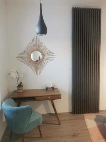 a desk with a blue chair and a mirror at Beli Apartman Mélygarázzsal in Hévíz