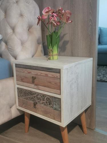 a vase with flowers on top of a wooden table at Beli Apartman Mélygarázzsal in Hévíz
