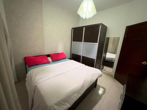- une chambre avec un lit et 2 oreillers rouges dans l'établissement Cozy Townhouse, with back yard (98), à Sheikh Zayed
