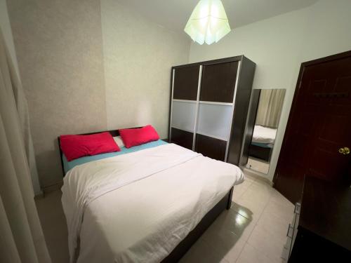 a bedroom with a bed with two red pillows at Cozy Townhouse, with back yard (98) in Sheikh Zayed