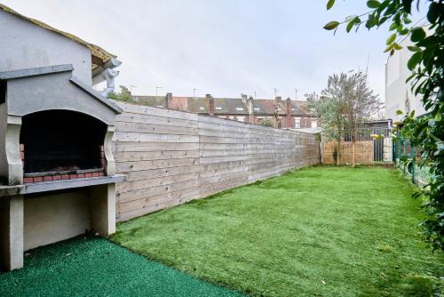 a retaining wall in a yard with a green lawn at 3 bedroom house with garden near St Maur tram in Marcq-en-Baroeul