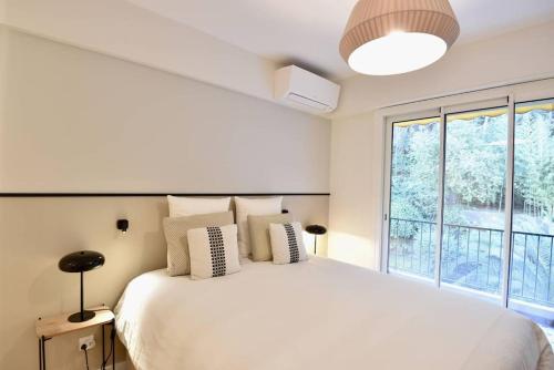 um quarto com uma grande cama branca e uma janela em Nice Signature Mont Alban em Nice