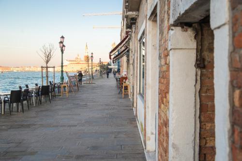 an empty street with tables and chairs next to the water at Ca Viola e Tobia by Venicevillas in Venice