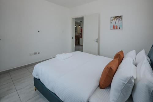 een slaapkamer met een bed met witte lakens en kussens bij The Avery Apartments at Odomaa Place, East Airport in Accra