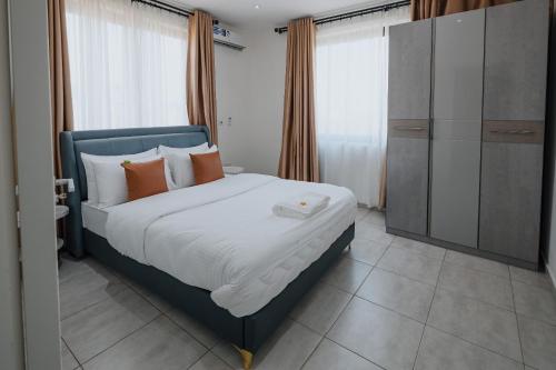 - une chambre avec un lit doté d'oreillers orange et blancs dans l'établissement The Avery Apartments at Odomaa Place, East Airport, à Accra