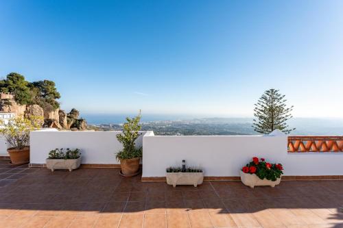 a patio with potted plants and a white wall at Sierra Mar Penthouse in Mijas