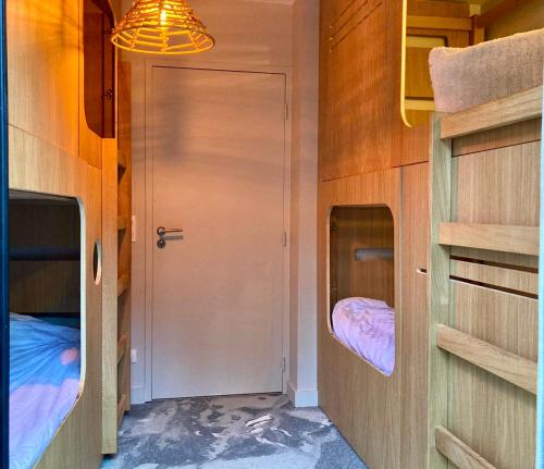 mały pokój z 2 łóżkami piętrowymi i drzwiami w obiekcie Chalets Patchwork w mieście Valloire