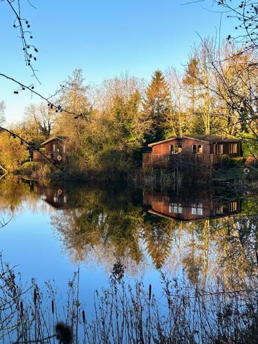 a house sitting on the side of a lake at 'Little Grebe' - Secluded Rustic Lodge - Fishermans delight. in York