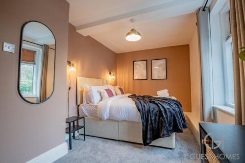 a bedroom with a large bed and a mirror at Guest Homes - Chandan Court Apartment in Bewdley