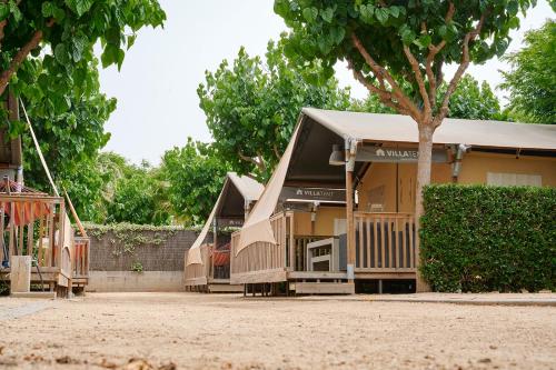 een huis met een veranda en een boom bij Glamping Blanes in Blanes