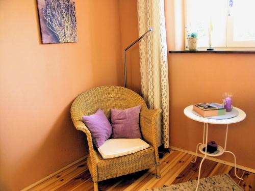 Una silla de mimbre con una almohada morada y una mesa. en Altes Backhaus, en Bad Harzburg