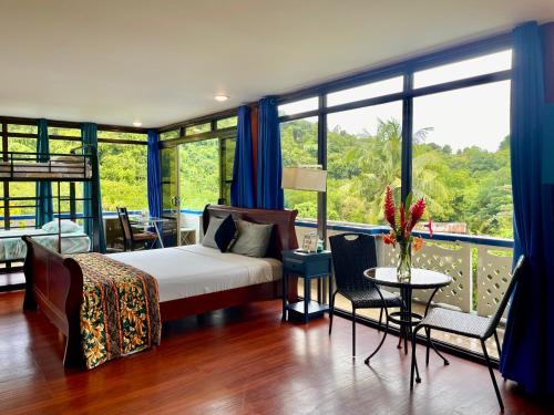 a bedroom with a bed and a balcony with windows at Ngermid Oasis- 1BD, Beautiful Lodge, Amazing Views in Koror