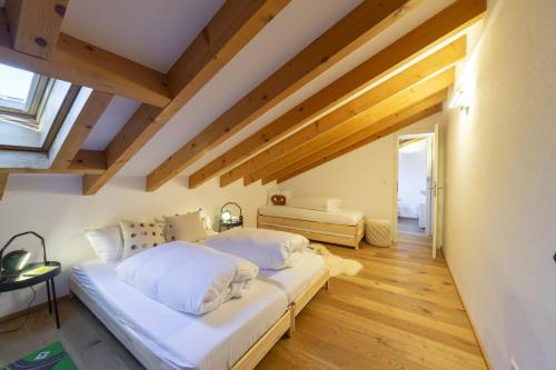 two beds in a room with wooden ceilings at Gamsalpblick in Wildhaus
