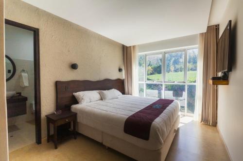 a bedroom with a bed and a large window at Life Hotel Valle Sagrado in Urubamba