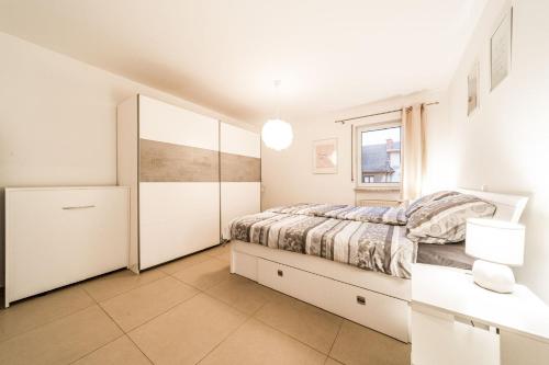 a white bedroom with a bed and a window at Beautiful apartment in the city and free parking in Luxembourg