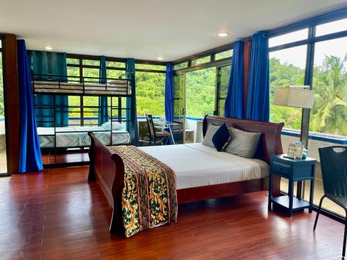 a bedroom with a bed in a room with windows at Ngermid Oasis-Spacious Studio With Kitchenette & Scenic Views in Koror