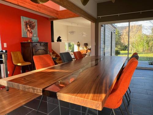 une salle à manger avec une table en bois et des chaises orange dans l'établissement LA PATTE D'OURS 2, à Ambon