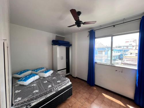 a bedroom with a bed with a ceiling fan and a window at Apartamento 106 in Cabo Frio