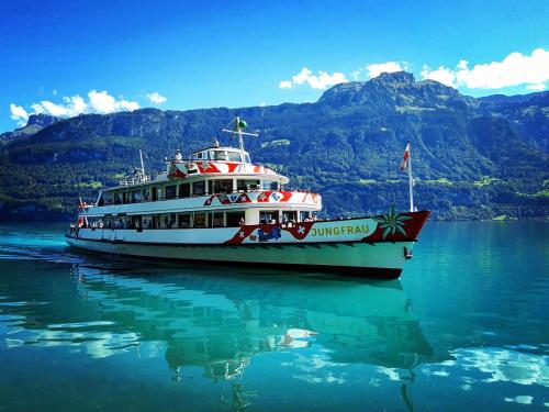 a boat on the water with mountains in the background at Chalet Lilo 2 Zimmer top mountain view in Beatenberg