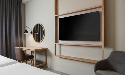 a hotel room with a flat screen tv on a wall at Hilton Garden Inn Bologna North in Bologna