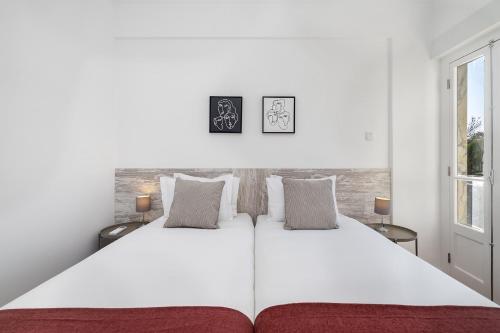 a white bedroom with a large white bed with two windows at WHome Peaceful Algés Family Home away from City Noise in Algés