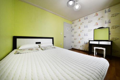 a bedroom with a large white bed and a desk at Gyeongju Namu Guesthouse in Gyeongju