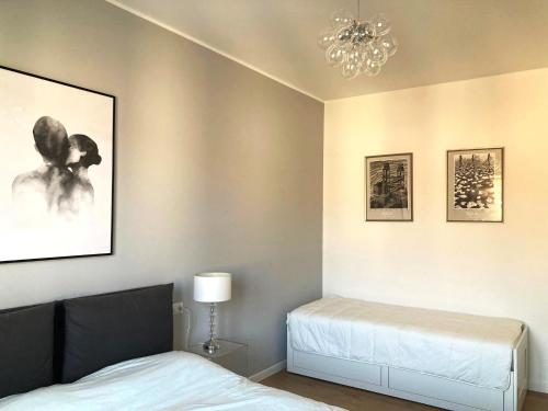 a bedroom with two beds and a chandelier at Bilocale moderno - Lorenteggio 145 in Milan