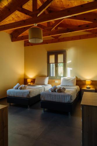 two beds in a room with wooden ceilings at Gea Mani Villas in Agios Nikolaos